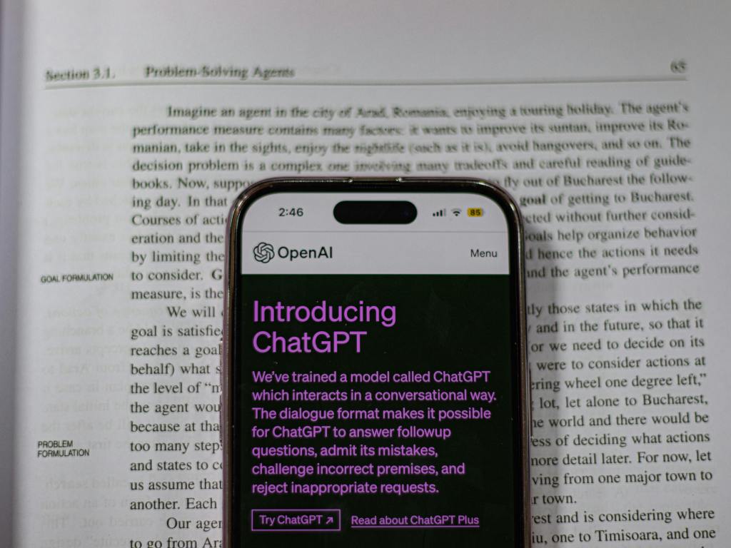 A mobile phone with the ChatGPT app open. The phone is on top of a book with text about problem solving 