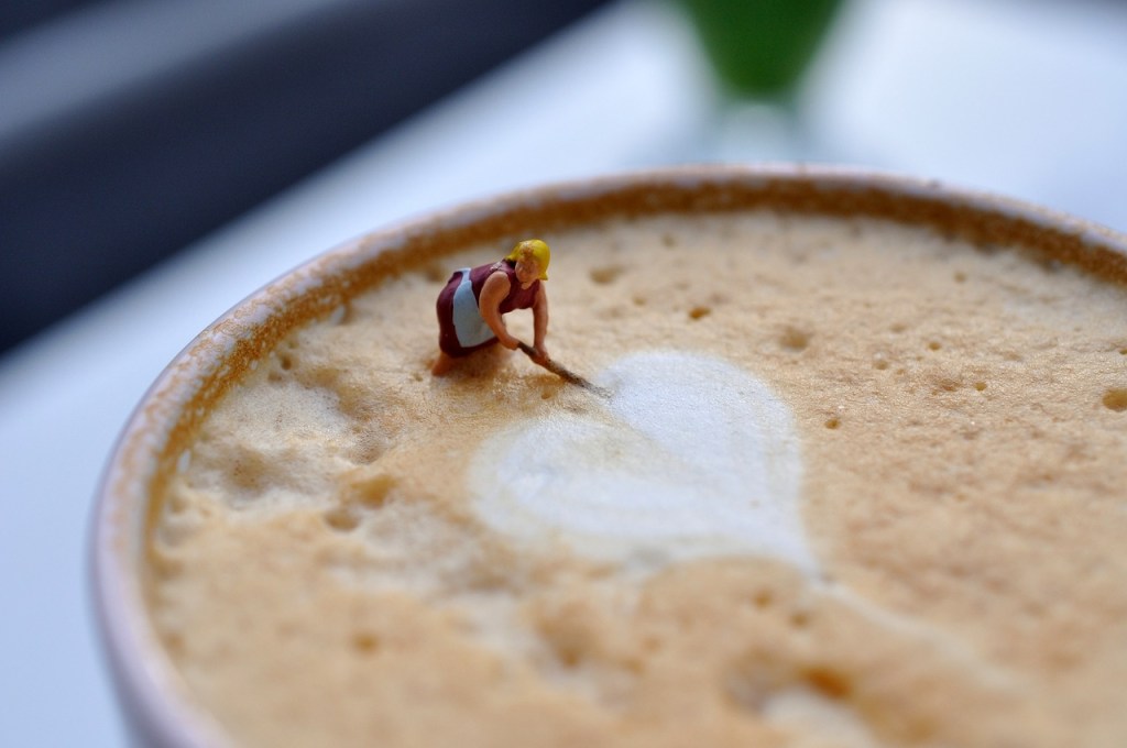 a model of a woman creating a heart on the top of some coffee foam
